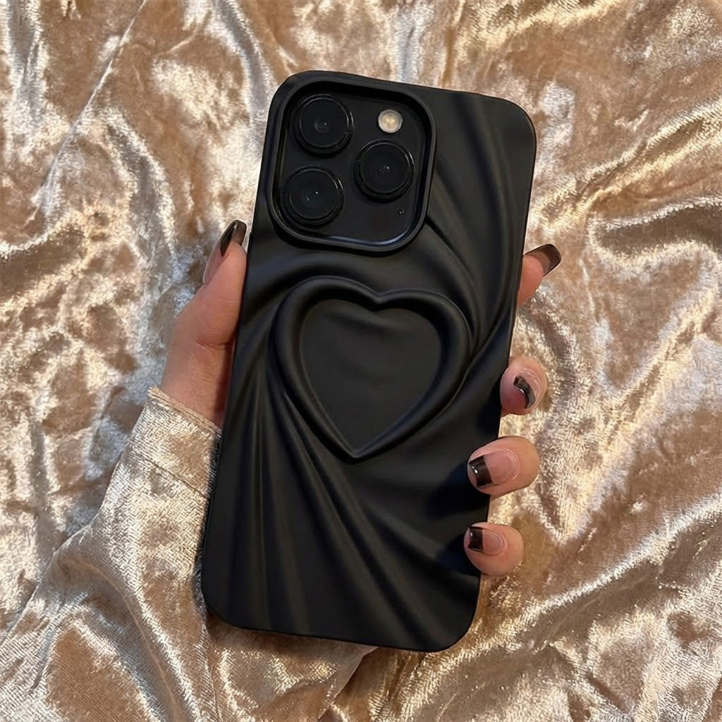 Black phone case with heart design held by a hand on a decorative surface