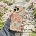Hand holding a phone with a floral case in a garden setting