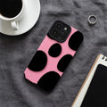 Pink phone case with black polka dots on a gray surface with a cup of coffee and notebook.